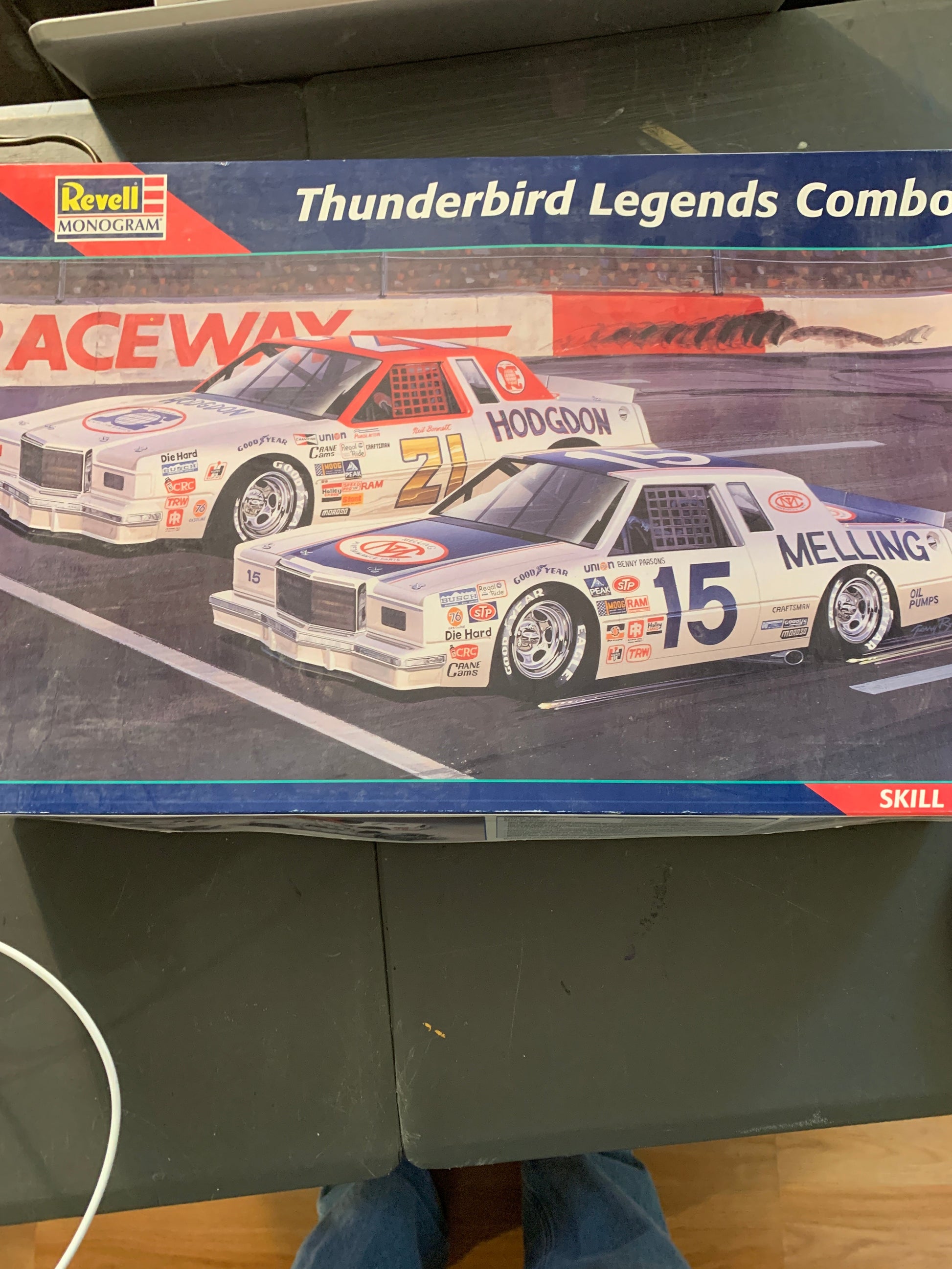 A boxed Revell model car set titled 'Thunderbird Legends Combo' shown on a dark table, with part of a person's legs visible at the right edge.