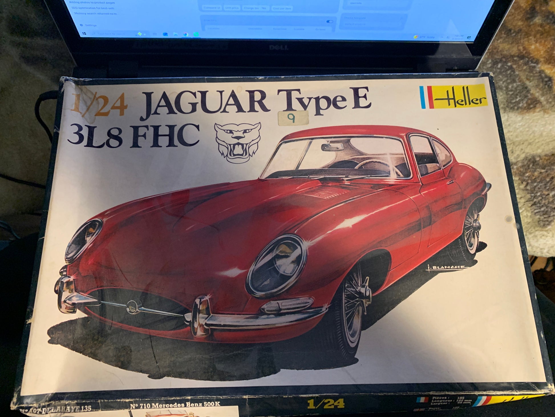 A 1:24 scale model kit box for a Jaguar Type E 318 FHC, featuring a red car illustration on the packaging, photographed next to a laptop screen.