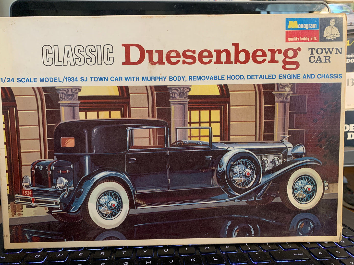 A 1/24 scale model kit box for the 'Classic Duesenberg Town Car' by Monogram. The packaging features an illustration of a black 1934 SJ Town Car with white-walled tires, set against a background of classical columns.