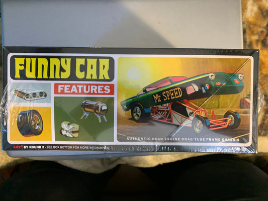 A boxed toy model car set photographed from above on a tabletop. The package front shows the title 'FUNNY CAR' in large yellow letters, a red 'FEATURES' panel, small feature icons, and a green and black die-cast car illustration.